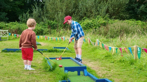 Two children playing mini golf during Summer of Play at Trerice, Cornwall.